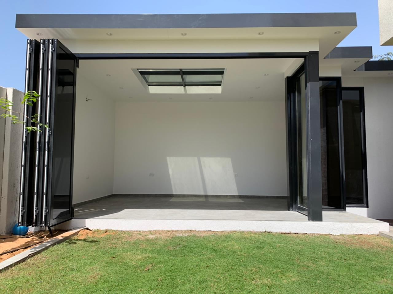 Black framed bi-folding doors fully open to a garden room - Zealcon