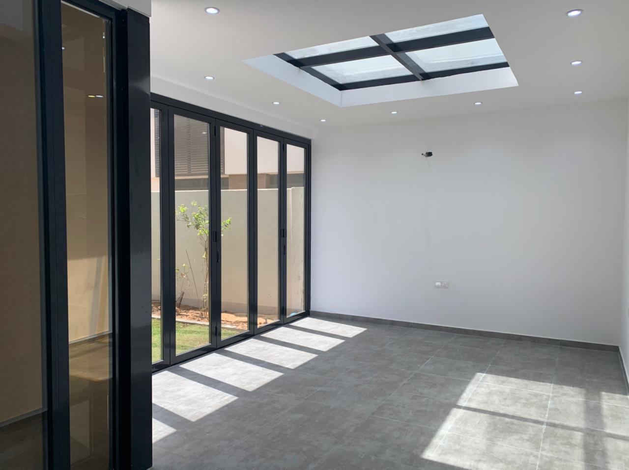 Black bi-folding door wall and skylight in a bright room - Zealcon