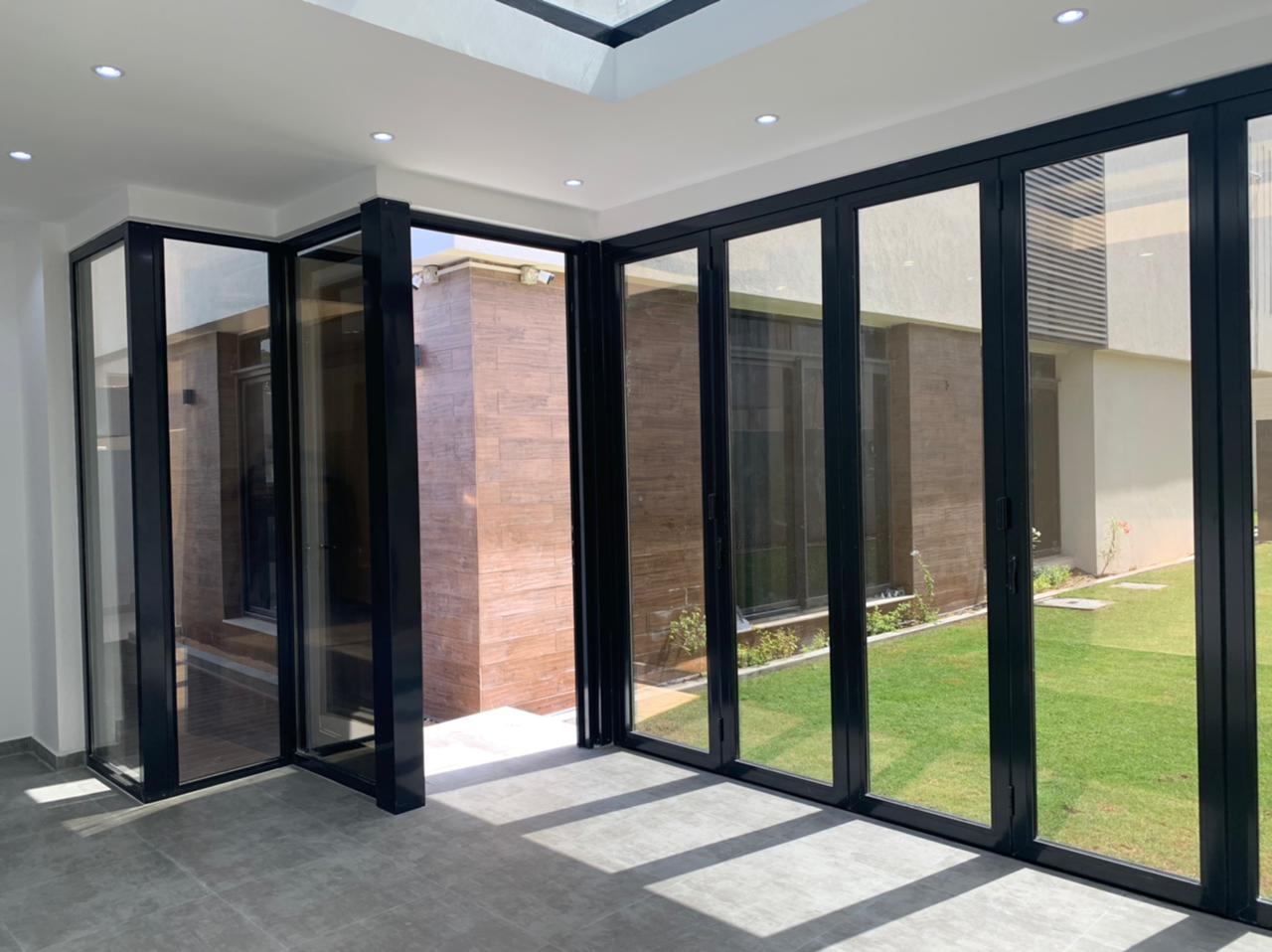 Bi-Folding Doors 6 Long black framed folding glass wall onto a garden - Zealcon