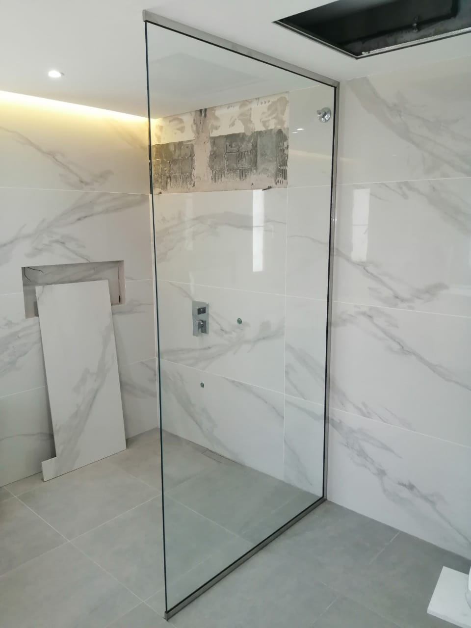 Umm Al Quwain 12 Frameless walk-in shower glass panel with slim black frame in a marble tiled bathroom - Zealcon