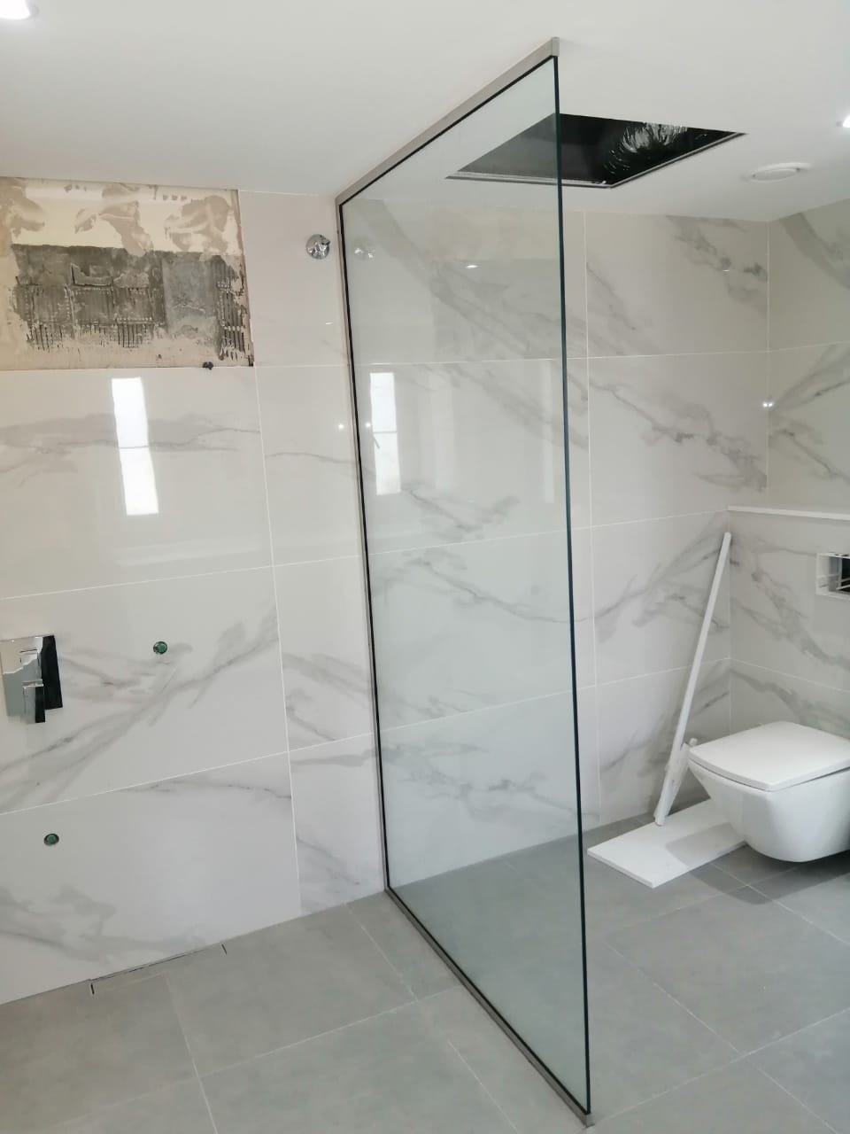 Shower Glass 2 Fixed glass walk-in shower panel installed in a bathroom during finishing - Zealcon