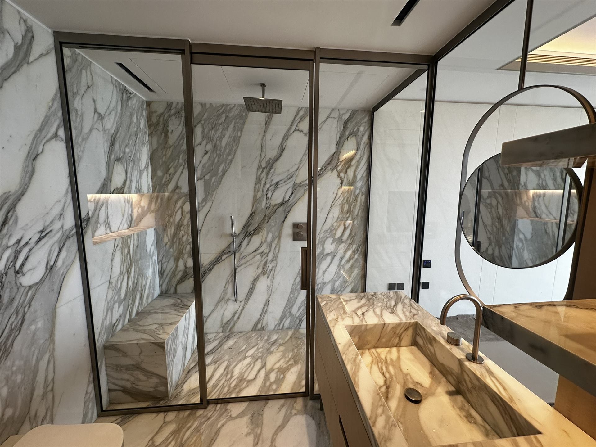 Sharjah 10 Floor-to-ceiling black framed multi-panel shower enclosure with marble walls - Zealcon